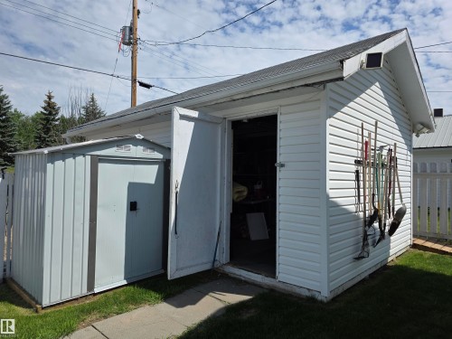 Two storage sheds featuring white vinyl siding and a metal-paneled structure - 5012 53 Ave, Breton, AB 