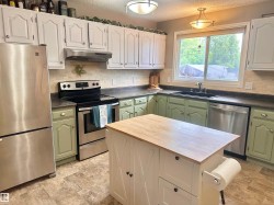 Kitchen featuring a central island with a wood-finish countertop, white cabinetry with barn door detailing, and integrated storage - 