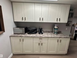 White cabinetry with brushed nickel hardware, complementing a speckled countertop. - 