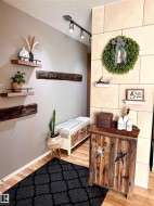 Entryway featuring track lighting, wood-finish flooring, and a decorative wall with a custom  stone-like hand painted surface. - 