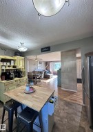 Kitchen featuring a portable butcher block island, textured ceiling, flush mount lighting, and wood-finish flooring. - 
