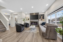 Open-concept living space featuring wood-finish flooring, recessed lighting, and a linear electric fireplace with stone-look surround - 