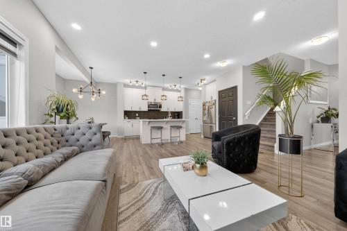 Expansive open-concept living area featuring wood-finish flooring, recessed lighting, and a contemporary kitchen - 6085 King Landing, Edmonton, AB - Indoor Photo Showing Living Room