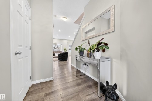 Entryway featuring warm wood-finish flooring, light neutral wall tones, and a mirrored console table - 6085 King Landing, Edmonton, AB - Indoor Photo Showing Other Room