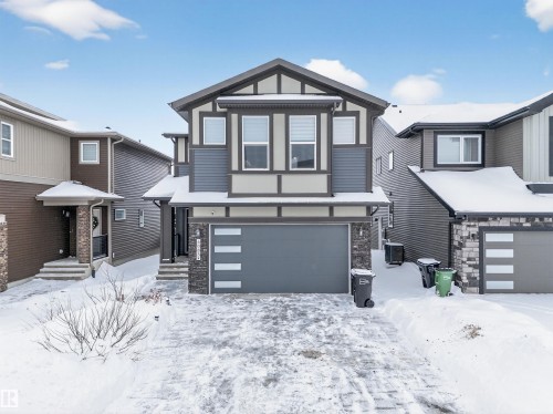 Contemporary two-story exterior featuring a two-car garage with modern panel detailing, a stone façade accent, and multiple large windows - 6085 King Landing, Edmonton, AB - Outdoor With Facade