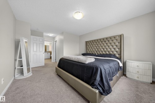 Carpeted bedroom featuring a neutral color palette, recessed lighting, and a doorway opening to a bathroom with a vanity and mirror - 6085 King Landing, Edmonton, AB - Indoor Photo Showing Bedroom