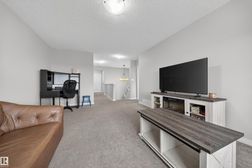 Carpeted living area featuring light gray wall paint, a built-in media console with storage, and recessed lighting - 6085 King Landing, Edmonton, AB - Indoor