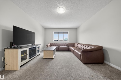 Spacious room featuring light gray walls, textured ceiling, a single window, and neutral-toned carpeting - 6085 King Landing, Edmonton, AB - Indoor Photo Showing Living Room