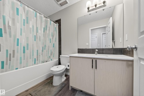 Bathroom featuring a light-toned vanity with black hardware, a built-in sink, a wall-mounted mirror, and a three-bulb light fixture - 6085 King Landing, Edmonton, AB - Indoor Photo Showing Bathroom