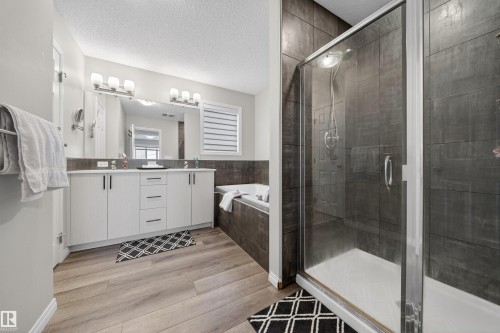 Bathroom featuring a glass-enclosed shower, a built-in bathtub, and a double vanity with two sinks - 6085 King Landing, Edmonton, AB - Indoor Photo Showing Bathroom