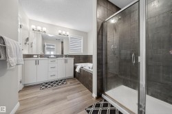 Bathroom featuring a glass-enclosed shower, a built-in bathtub, and a double vanity with two sinks - 