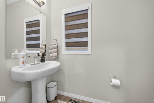 Pedestal sink with chrome faucet, a rectangular mirror, and a window with horizontal blinds - 6085 King Landing, Edmonton, AB - Indoor Photo Showing Bathroom