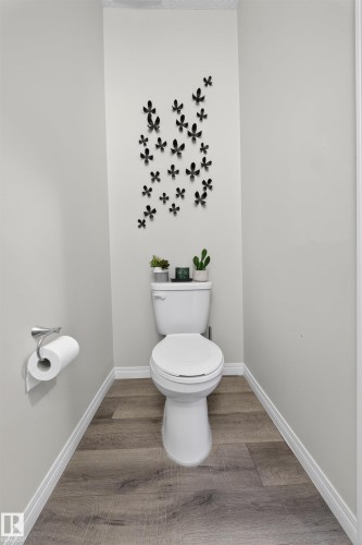 Powder room featuring light gray walls, wood-finish flooring, and crisp white baseboards - 6085 King Landing, Edmonton, AB - Indoor Photo Showing Bathroom