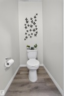 Powder room featuring light gray walls, wood-finish flooring, and crisp white baseboards - 