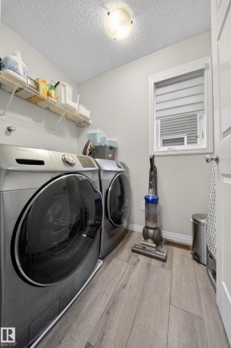 Utility room featuring wood-finish flooring, a flush-mount ceiling light fixture, and a window with blinds - 6085 King Landing, Edmonton, AB - Indoor Photo Showing Laundry Room