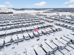 Residential neighborhood featuring multiple detached homes with snow-covered roofs and a distant treeline - 