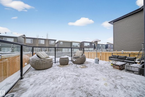Spacious outdoor patio area featuring a glass panel railing system, light wood fencing, and a dark grey exterior wall - 6085 King Landing, Edmonton, AB - Outdoor