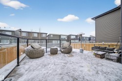 Spacious outdoor patio area featuring a glass panel railing system, light wood fencing, and a dark grey exterior wall - 