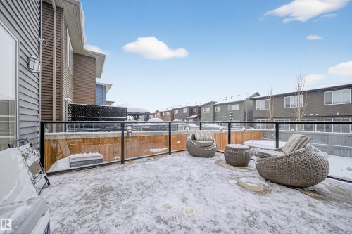Exterior deck featuring a glass and metal railing system, wood privacy fence, and a wall-mounted outdoor light fixture - 6085 King Landing, Edmonton, AB - Outdoor