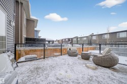 Exterior deck featuring a glass and metal railing system, wood privacy fence, and a wall-mounted outdoor light fixture - 