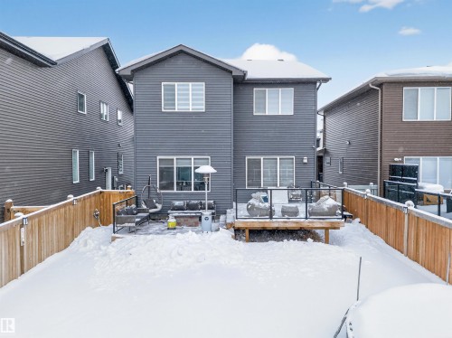 Rear exterior with charcoal horizontal siding, a ground-level patio, and an elevated wood-finish deck with glass panel railings - 6085 King Landing, Edmonton, AB - Outdoor With Exterior