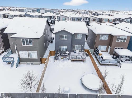 Two-story property featuring a fenced backyard with a wood deck and glass railings - 6085 King Landing, Edmonton, AB - Outdoor