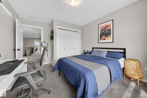 Carpeted bedroom featuring a double-door closet, light gray wall paint, and a built-in wall shelf - 3337 Kulay Way, Edmonton, AB - Indoor Photo Showing Bedroom