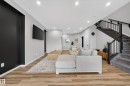 Spacious living area featuring wood-finish flooring, recessed lighting, and a modern staircase with black railings - 3337 Kulay Way, Edmonton, AB  - Indoor 
