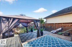 Spacious exterior deck featuring a gazebo, wood privacy fencing, and wood-finish decking - 