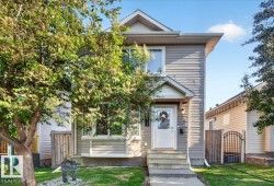 Two-story residential exterior featuring light-colored siding, a white entry door with a storm door, and an overhead lighting fixture - 