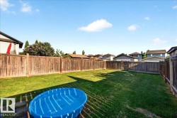 Expansive rear yard featuring a manicured lawn, full wood fencing, and a rear gate - 