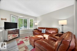Living space featuring a bay window, light grey walls, and wood-finish flooring - 