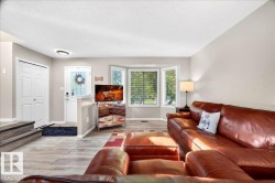 Living area featuring wood-finish flooring, a bright bay window, and a white front entry door with a glass insert - 