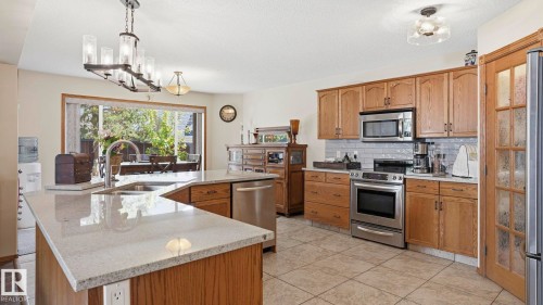 Kitchen featuring wood cabinetry, stainless steel appliances, and light-toned tile flooring - 4309 37A Avenue, Edmonton, AB - Indoor Photo Showing Kitchen With Double Sink