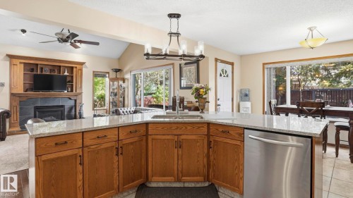 Kitchen island featuring granite-style countertops, integrated sink, and stainless steel dishwasher - 4309 37A Avenue, Edmonton, AB - Indoor Photo Showing Kitchen With Double Sink