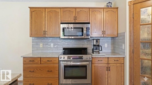 Kitchen featuring wood cabinetry, stainless steel appliances, light-toned countertops, and a subway tile backsplash - 4309 37A Avenue, Edmonton, AB - Indoor Photo Showing Kitchen