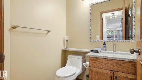 Bathroom vanity featuring a granite-finish countertop, undermount sink, and wood-finish cabinetry - 4309 37A Avenue, Edmonton, AB - Indoor Photo Showing Bathroom