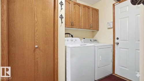 Laundry area featuring upper wood cabinetry, white appliances, and a solid wood bifold door - 4309 37A Avenue, Edmonton, AB - Indoor Photo Showing Laundry Room