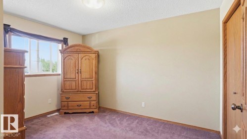 Bright interior room featuring a large window with white trim, neutral wall paint, and purple carpeting - 4309 37A Avenue, Edmonton, AB - Indoor