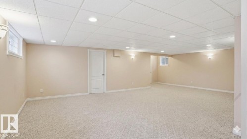 Spacious room featuring neutral carpeting, light beige walls, a drop ceiling with recessed lighting, and white trim - 4309 37A Avenue, Edmonton, AB - Indoor Photo Showing Basement