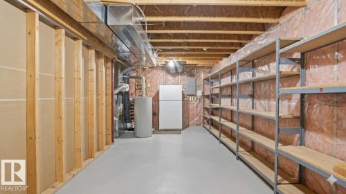 Unfinished basement featuring exposed wood framing, concrete flooring, insulated walls, and extensive built-in metal shelving - 4309 37A Avenue, Edmonton, AB - Indoor Photo Showing Basement