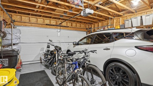Spacious garage featuring exposed wood framing, an automatic garage door opener, and a gray epoxy-coated floor - 4309 37A Avenue, Edmonton, AB - Indoor Photo Showing Garage