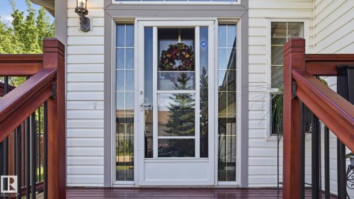 White vinyl siding exterior with a storm door, flanked by sidelight windows and a transom window above - 4309 37A Avenue, Edmonton, AB - Outdoor With Exterior