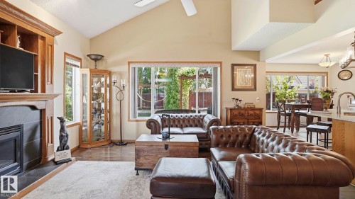 Open-concept living area featuring vaulted ceilings, a built-in entertainment center with a fireplace, large windows, and wood-finish flooring - 4309 37A Avenue, Edmonton, AB - Indoor Photo Showing Living Room With Fireplace