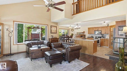 Vaulted living area with wood-finish flooring, a ceiling fan, and a large window overlooking a landscaped yard with a pergola - 4309 37A Avenue, Edmonton, AB - Indoor
