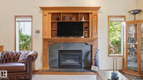 Integrated fireplace with a dark tile surround and hearth, featuring a wood mantelpiece and built-in shelving - 4309 37A Avenue, Edmonton, AB - Indoor Photo Showing Living Room With Fireplace