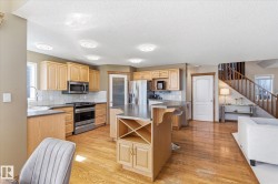 Kitchen featuring natural wood cabinetry, stainless steel appliances, a tile backsplash, and an island with a built-in wine rack - 