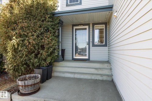 Inviting front entrance featuring a glass storm door, an adjacent sidelite window, and a covered porch - 442 Hunters Green, Edmonton, AB - Outdoor With Exterior