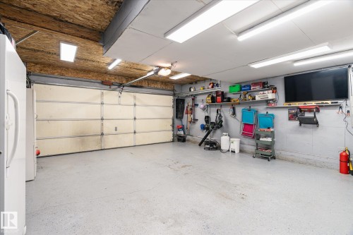 Spacious garage featuring a large automatic overhead door, concrete flooring, and ample overhead lighting - 442 Hunters Green, Edmonton, AB - Indoor Photo Showing Garage