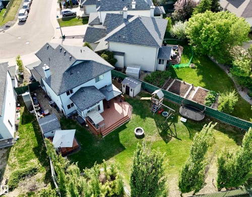 Expansive backyard featuring a multi-tiered wood-finish deck, integrated outdoor fire pit, and terraced garden beds - 442 Hunters Green, Edmonton, AB - Outdoor